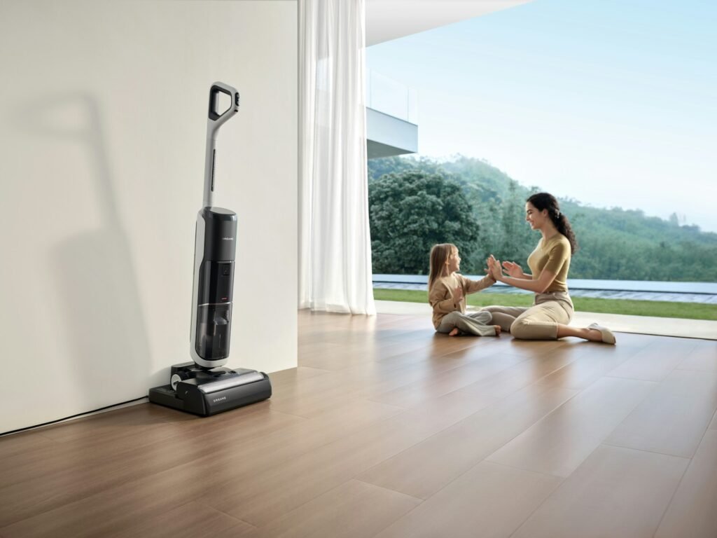 Woman and child playing near vacuum cleaner.