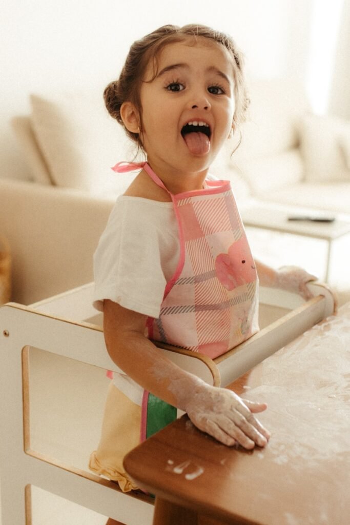 A young girl with flour on her face and hands
