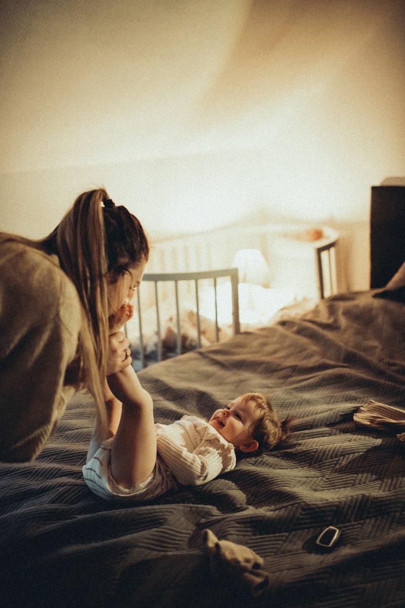 a little girl laying on top of a bed next to a woman
