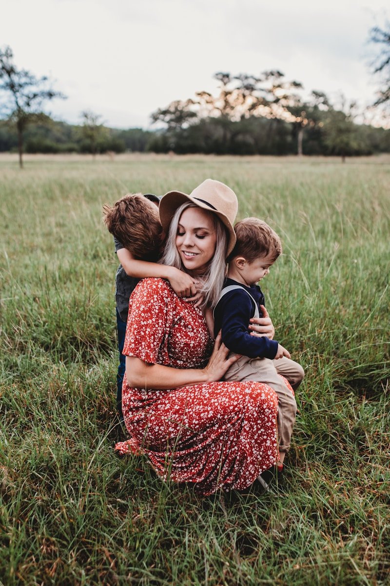 man and two children on grass field