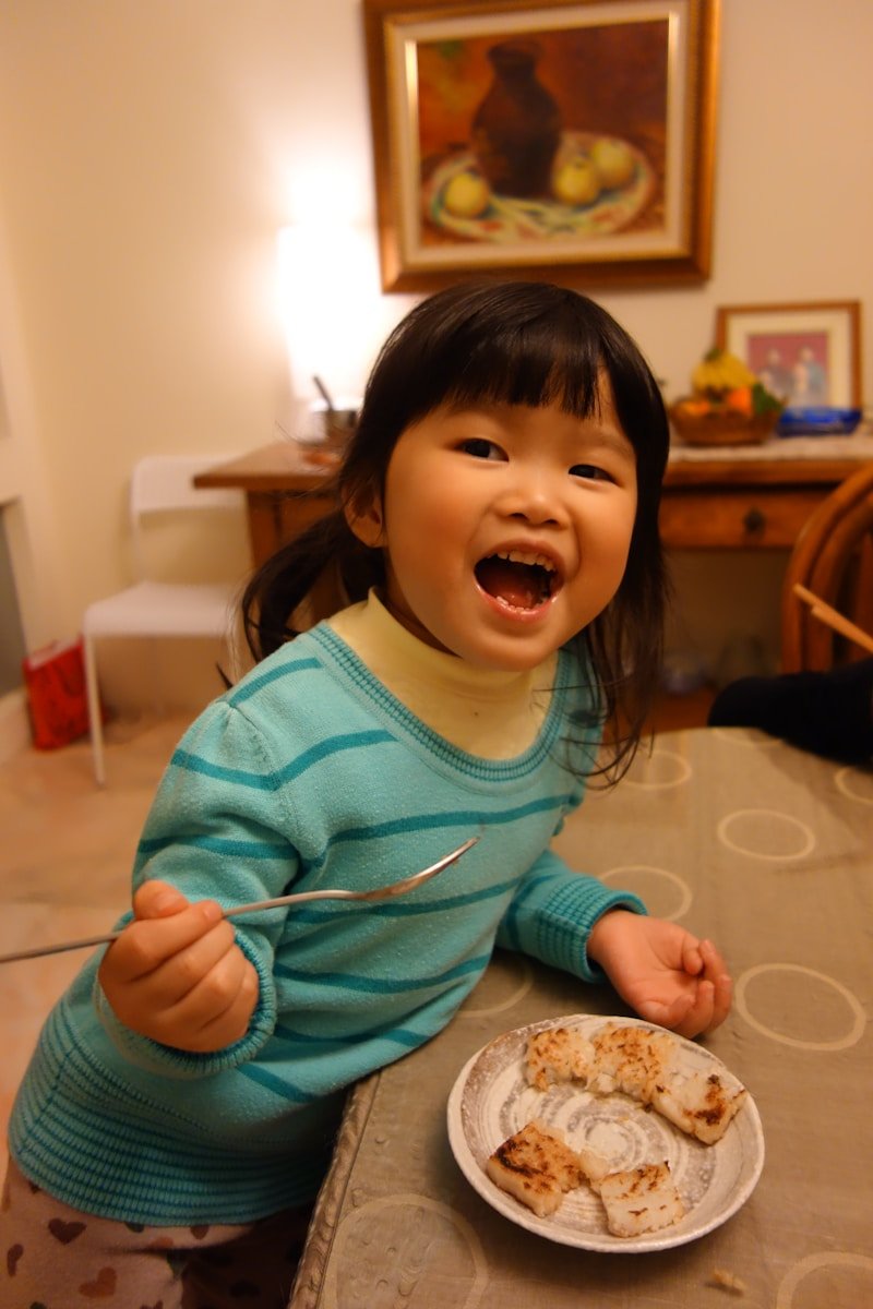A happy young girl eating at a table.