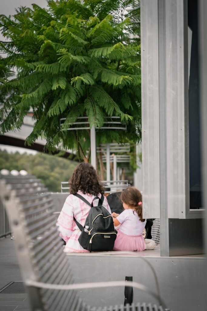 a woman and a little girl sitting on a bench